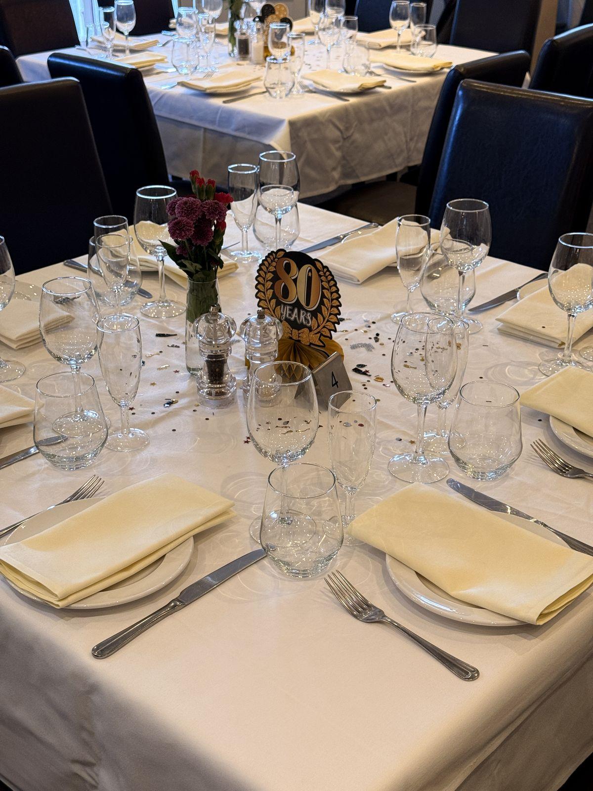 Birthday table with glassware, napkins and an 80th centrepiece