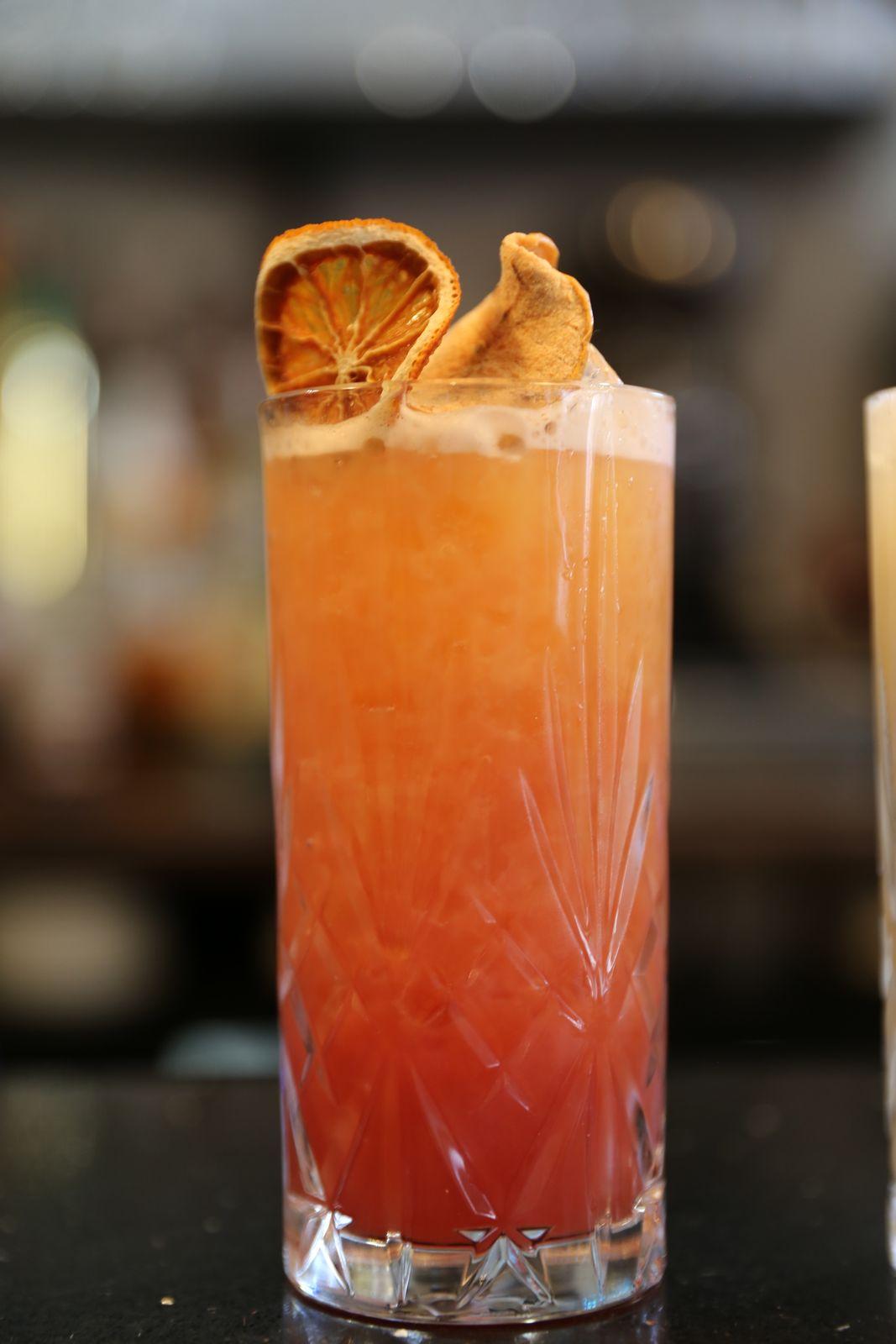 A tall orange spritz garnished with dried citrus