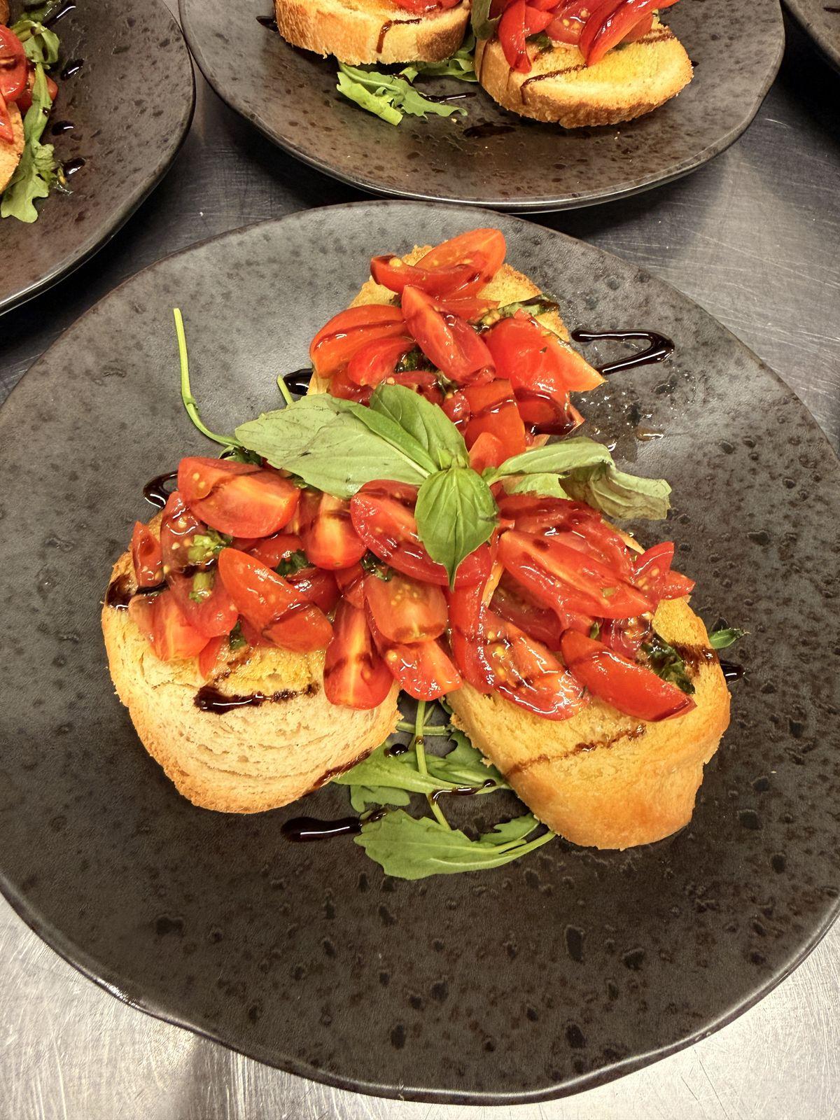 Toasted bread topped with plum tomatoes and basil