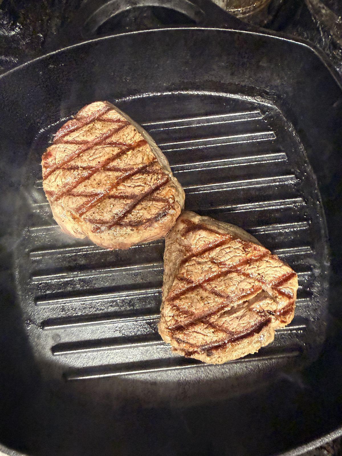 Two steaks char-grilling in the kitchen