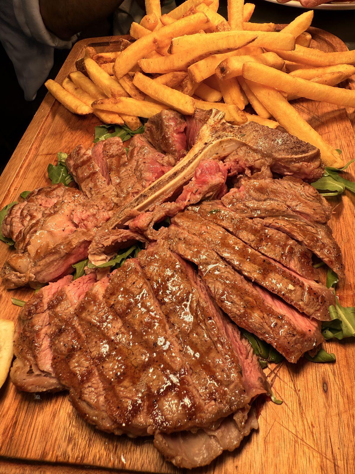 Tomahawk steak sliced with rocket and chips