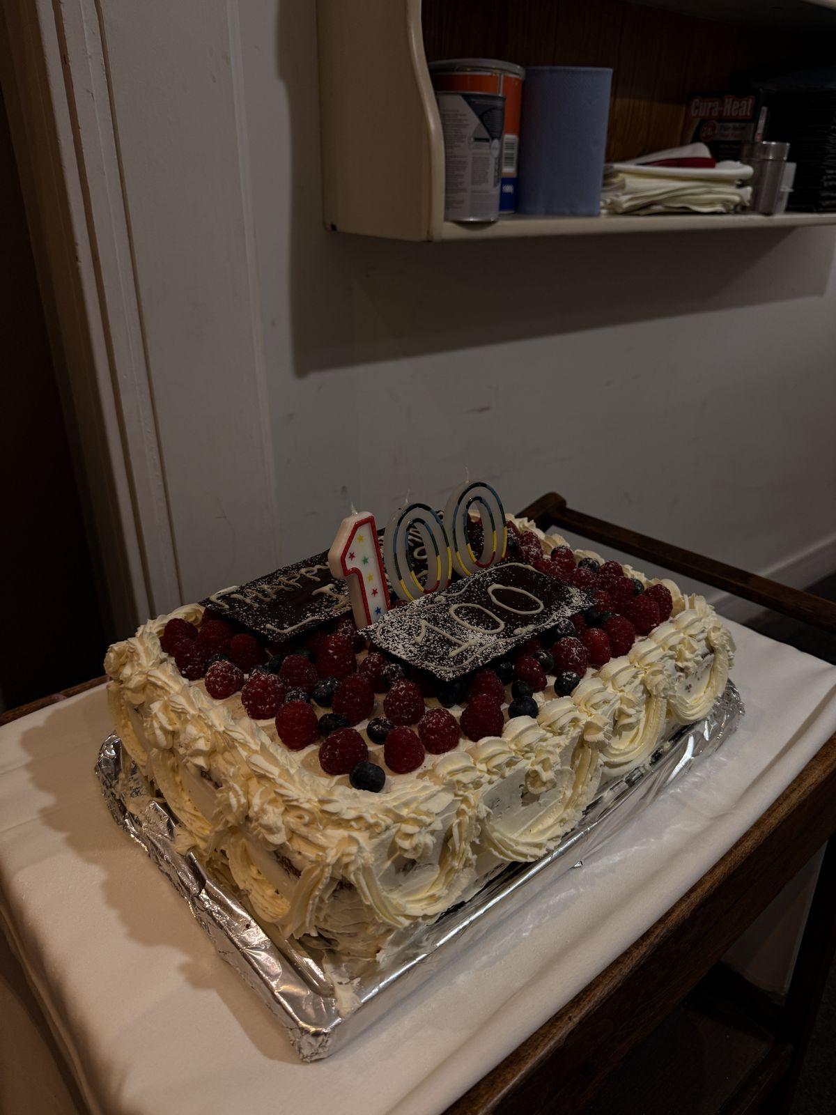 Berry-topped cake with a 100 candle