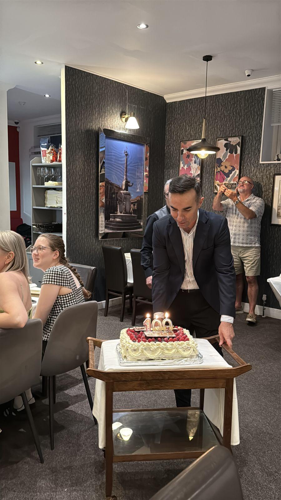 Guests gathered around a 100th birthday cake